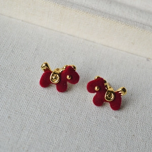 Red flocked dog stud earrings with gold metal accents on a grey textured background