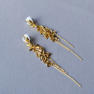 Vue détaillée des boucles d'oreilles feuilles dorées avec pampilles et pierres fines