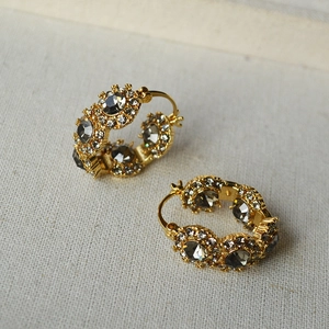 Detailed close-up of retro brass earrings with grey crystals and shimmering rhinestones