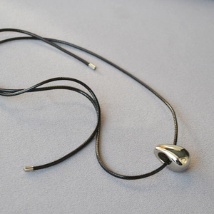 Minimalist silver water drop pendant necklace with sleek black cord on grey background