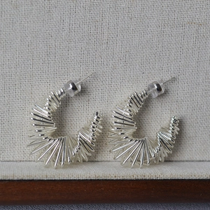 Gros plan de boucles d'oreilles argentées en forme de C avec motif filaire torsadé