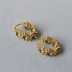 Close-up of vintage gold-plated hoop earrings with grey faceted crystals and sparkling details