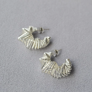 Vue macro des boucles d'oreilles argentées en forme de C au design minimaliste