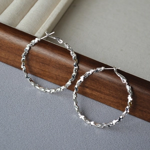 Detailed view of silver hoop earrings with textured geometric facets on a jewelry display