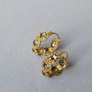 Detail of vintage gold plated earrings featuring grey crystals and sparkling rhinestones