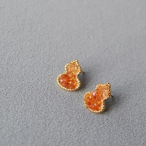 Macro detail of gourd shaped earrings with orange crystal and micro paved zircons