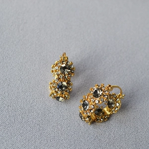 Macro detail of gold-plated flower earrings with grey crystals and shimmering diamonds