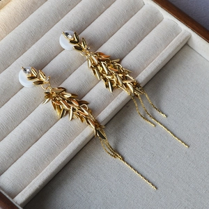 Vue détaillée de boucles d'oreilles épi de blé doré avec franges sur velours gris