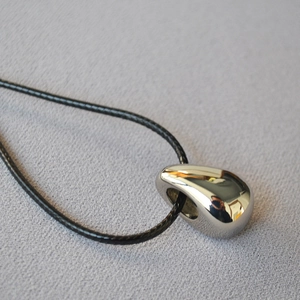 Macro shot of polished teardrop pendant with minimalist black cord necklace