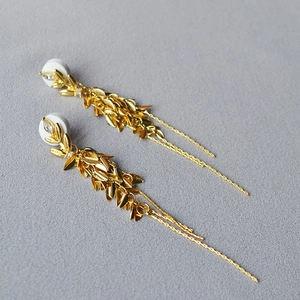 Détail des boucles d'oreilles feuilles dorées avec pampilles et pierres gouttes