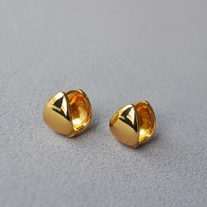 Macro shot of polished gold-plated brass teardrop earrings with a minimal glossy finish
