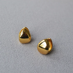 Detailed macro view of polished gold teardrop earrings with smooth metallic finish