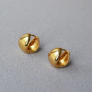 Macro view of chunky golden teardrop hoop earrings with a polished mirror finish
