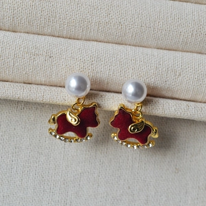 Close-up of red flocked horse earrings with pearls and gold plating for women