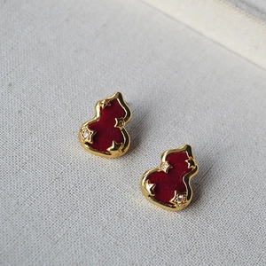 Détail de boucles d'oreilles gourde en velours rouge avec étoiles dorées et zircones