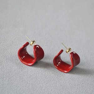 Macro shot of red enamel C-shaped earrings with polished finish and gold-tone studs