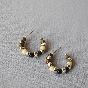 Detailed close-up of C-shaped hoop earrings with tiger eye stone and silver beads