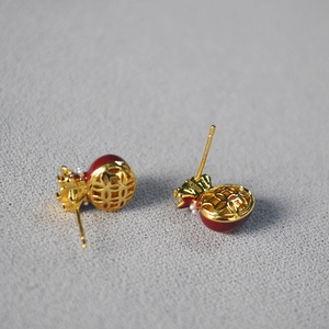 Macro detail of red glaze money bag stud earrings with gold hollowed coin pattern