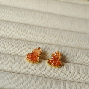 Detailed close-up of amber crystal gourd earrings on a beige velvet jewelry display