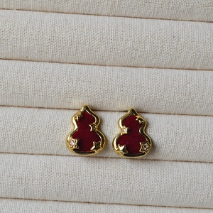 Détail macro de boucles d'oreilles gourde en velours rouge avec étoiles dorées et cristaux