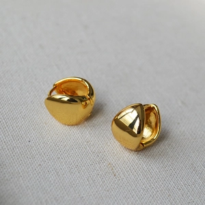 Detailed close-up of chunky gold-plated brass teardrop earrings on gray fabric