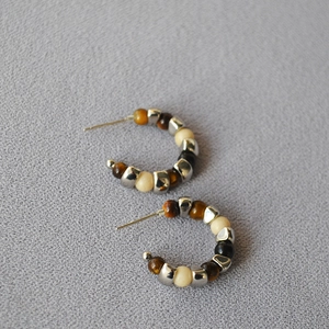 Detailed close-up of C-shaped silver beaded earrings with natural tiger eye stones