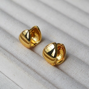 Macro shot of polished gold-plated brass teardrop earrings in a cream jewelry box