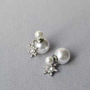 Detailed view of white double pearl earrings with a sparkling snowflake crystal pendant