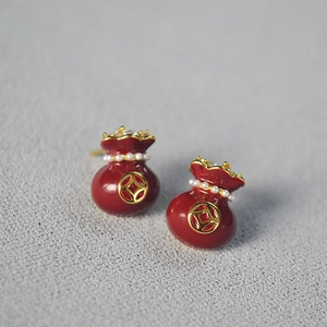 Macro shot of red enamel money bag earrings with mini pearls and gold coin detail