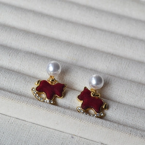 Detailed macro view of red flocked rocking horse earrings with pearls on a jewelry tray