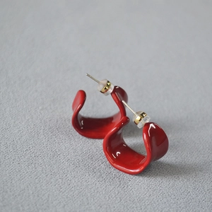 Macro shot of red enamel wave earrings with glossy finish and secure metal butterfly backs