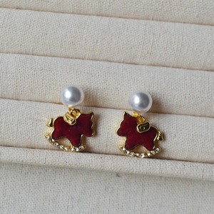 Detail of red flocked rocking horse earrings with pearls and crystals on a display tray