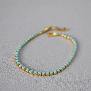 Elegant gold-plated tennis bracelet featuring turquoise blue beads and secure claw setting