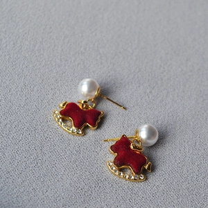 Macro detail of red flocked rocking horse earrings with pearls and crystals