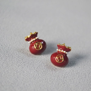 Detailed macro view of red enamel money bag stud earrings with gold coins and small pearls