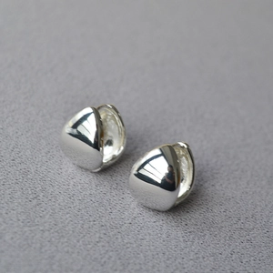 Macro shot of polished silver teardrop earrings with a smooth mirror finish on fabric