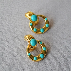 Detailed macro of vintage brass earrings with turquoise stones and gold-plated hoops