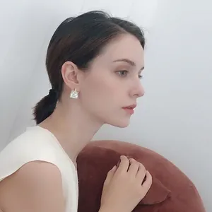 Elegant shell mosaic square stud earrings in 925 silver worn by a model on a warm background