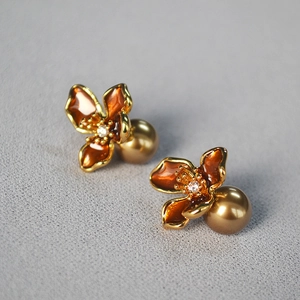 Detailed close-up of champagne pearl earrings with amber enamel flower petals and gold trim