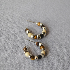 Detailed view of silver-toned C-shaped hoop earrings with tiger eye and mixed resin beads
