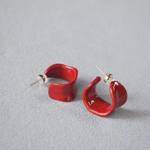 Detail of red enamel C-shaped wave stud earrings with silver needles and soft backings