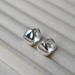 Macro shot of silver-plated brass drop earrings with high-polish finish on jewelry tray