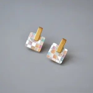 Detailed macro view of square earrings with mosaic shell inlays and matte gold studs
