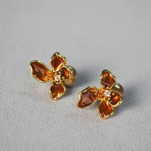Detailed view of champagne floral earrings with red enamel and silver needle backing
