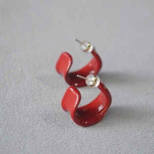 Detail of red enamel hoop earrings with silver pins and secure silicone backings