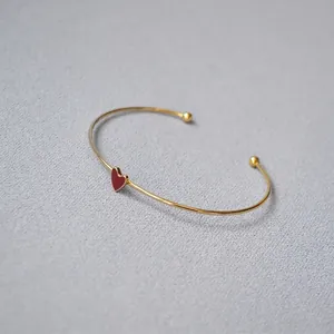 Minimalist gold-plated open bangle with red enamel heart and metal ball ends