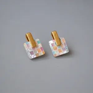 Macro detail of square mosaic mother of pearl earrings with brushed gold finish hooks