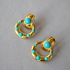 Detailed shot of vintage brass gold earrings with turquoise stones and milgrain texture