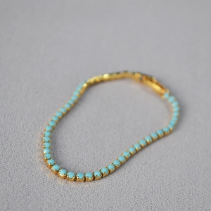 Close-up of gold turquoise bead bracelet featuring elegant claw setting and tennis chain style