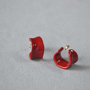 Close-up of vibrant red enamel C-shaped hoop earrings with polished glossy finish